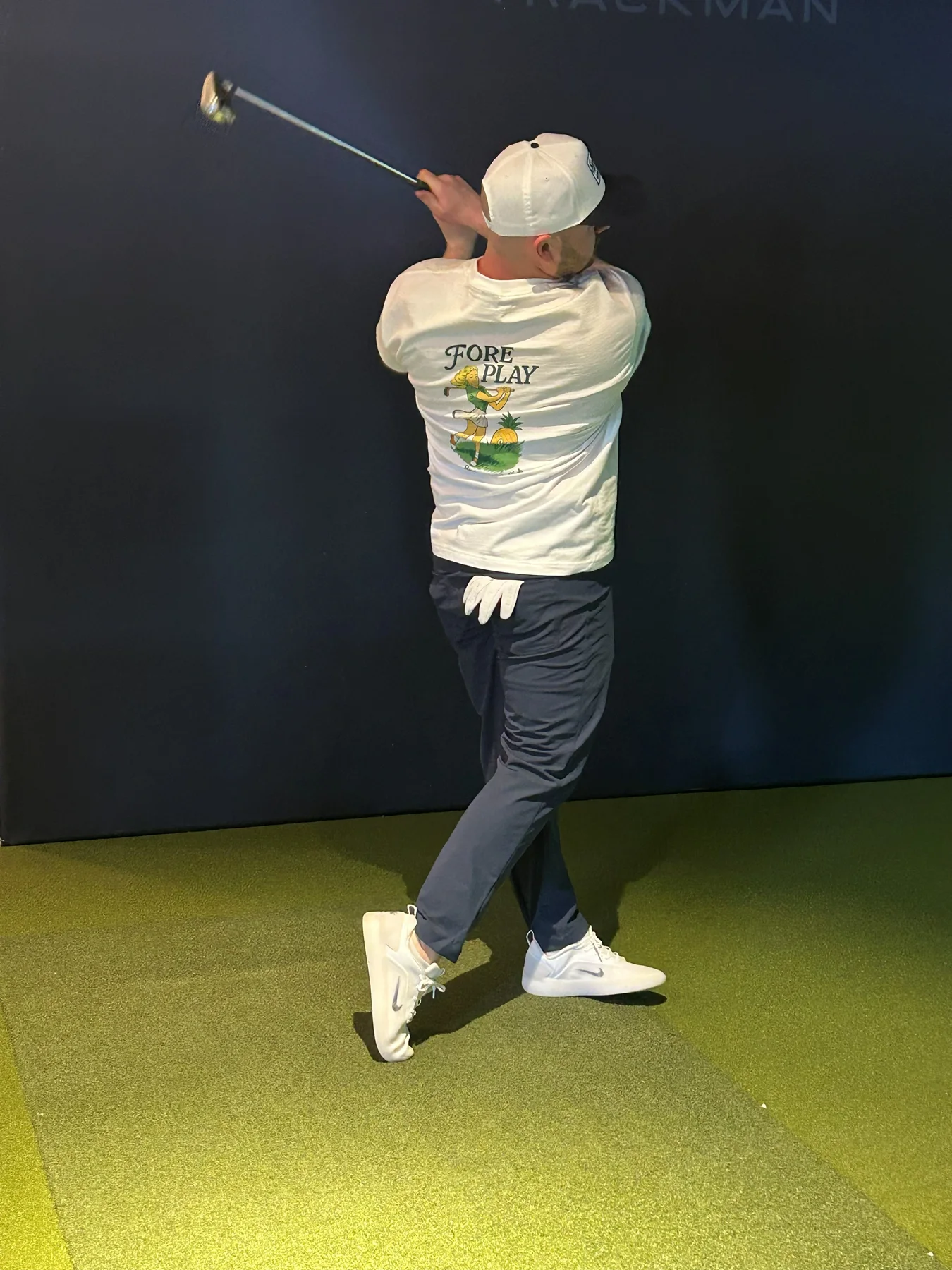 Guest in a Fore Play tee swinging in the simulator bay.